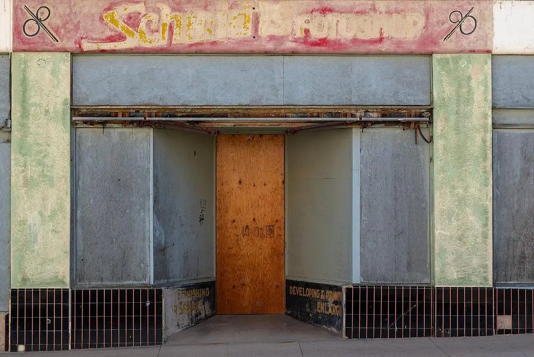 Vacant storefront with papered windows between tenants